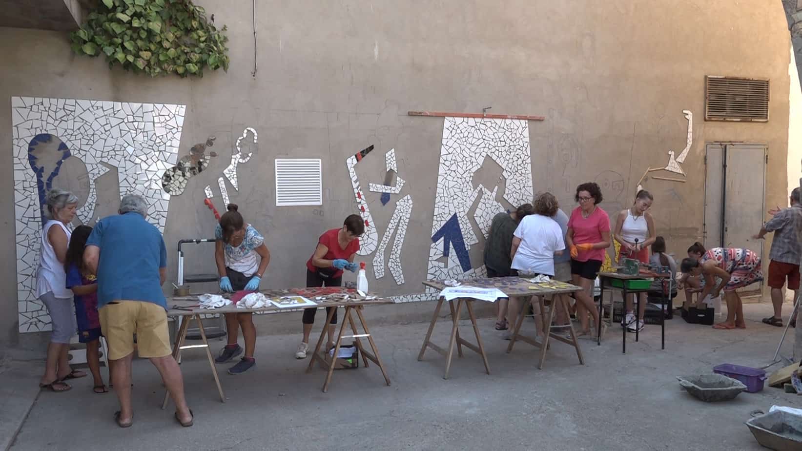 Voluntaris elaboren un mosaic amb trencadís per decorar la biblioteca de Bellcaire d’Urgell